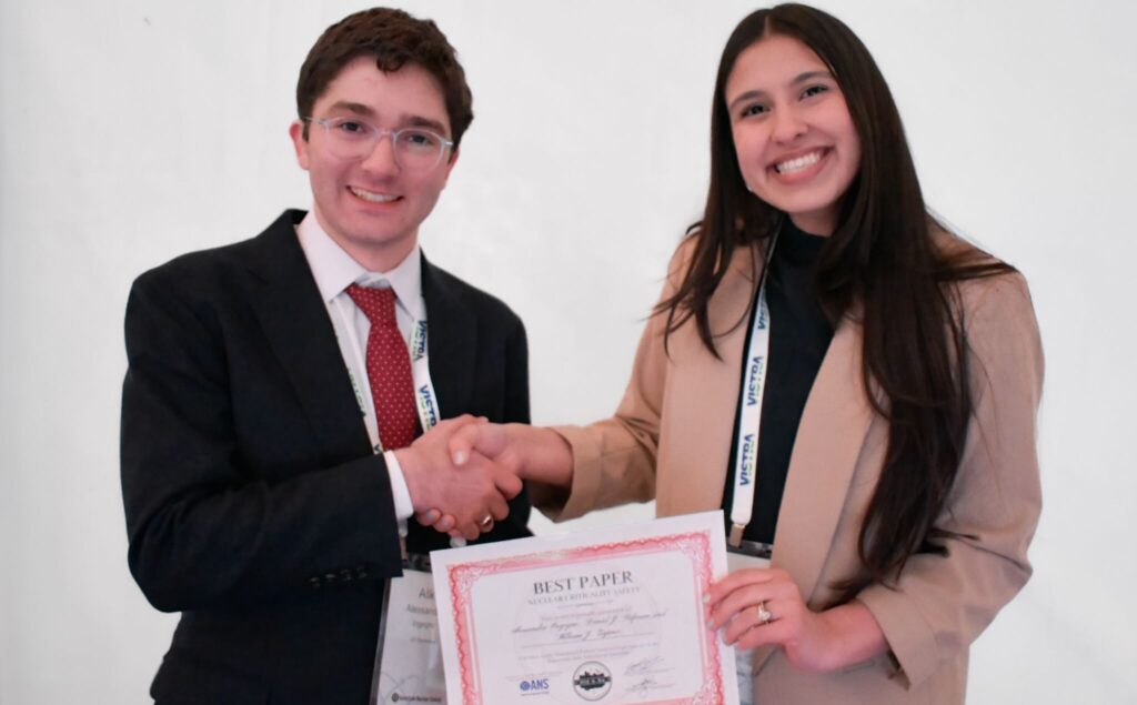 Alessandro Ingegno shaking hands holding his Best Paper award certificate